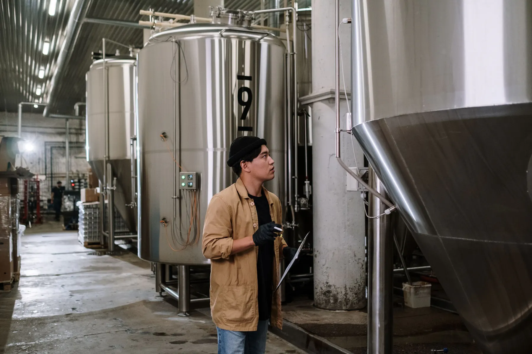 Production specialist inspecting large stainless-steel vessels