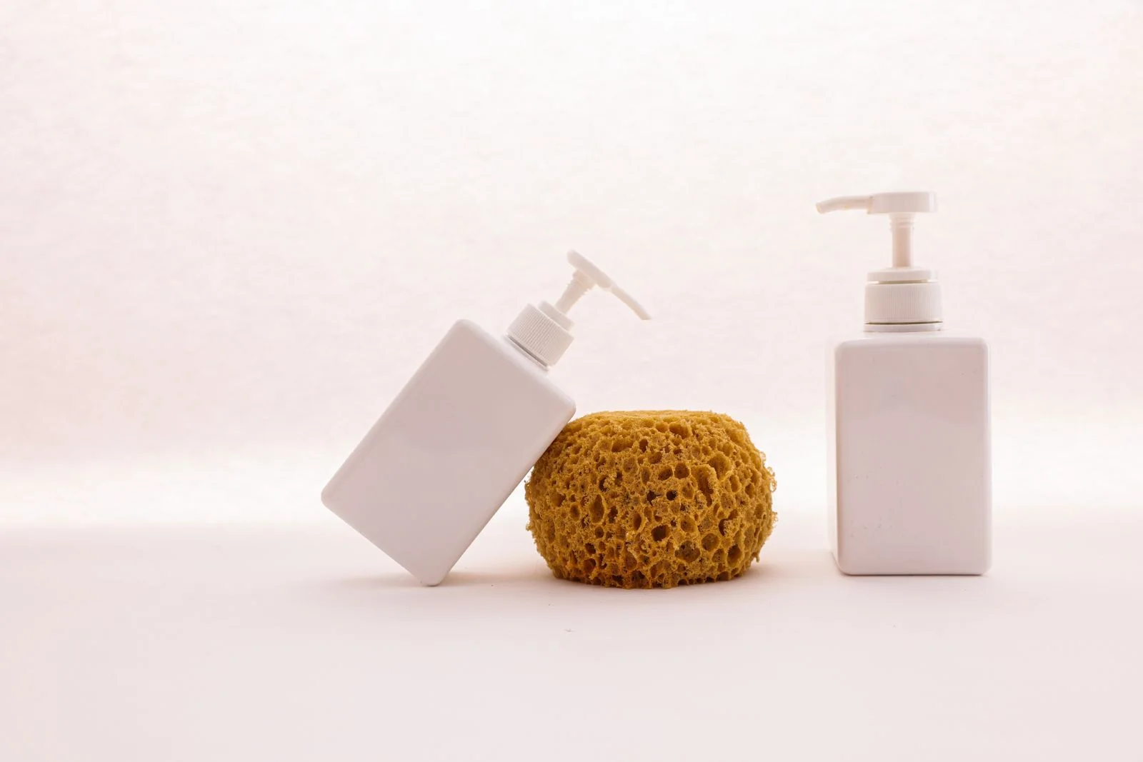Blank white pump bottles arranged with a natural sponge