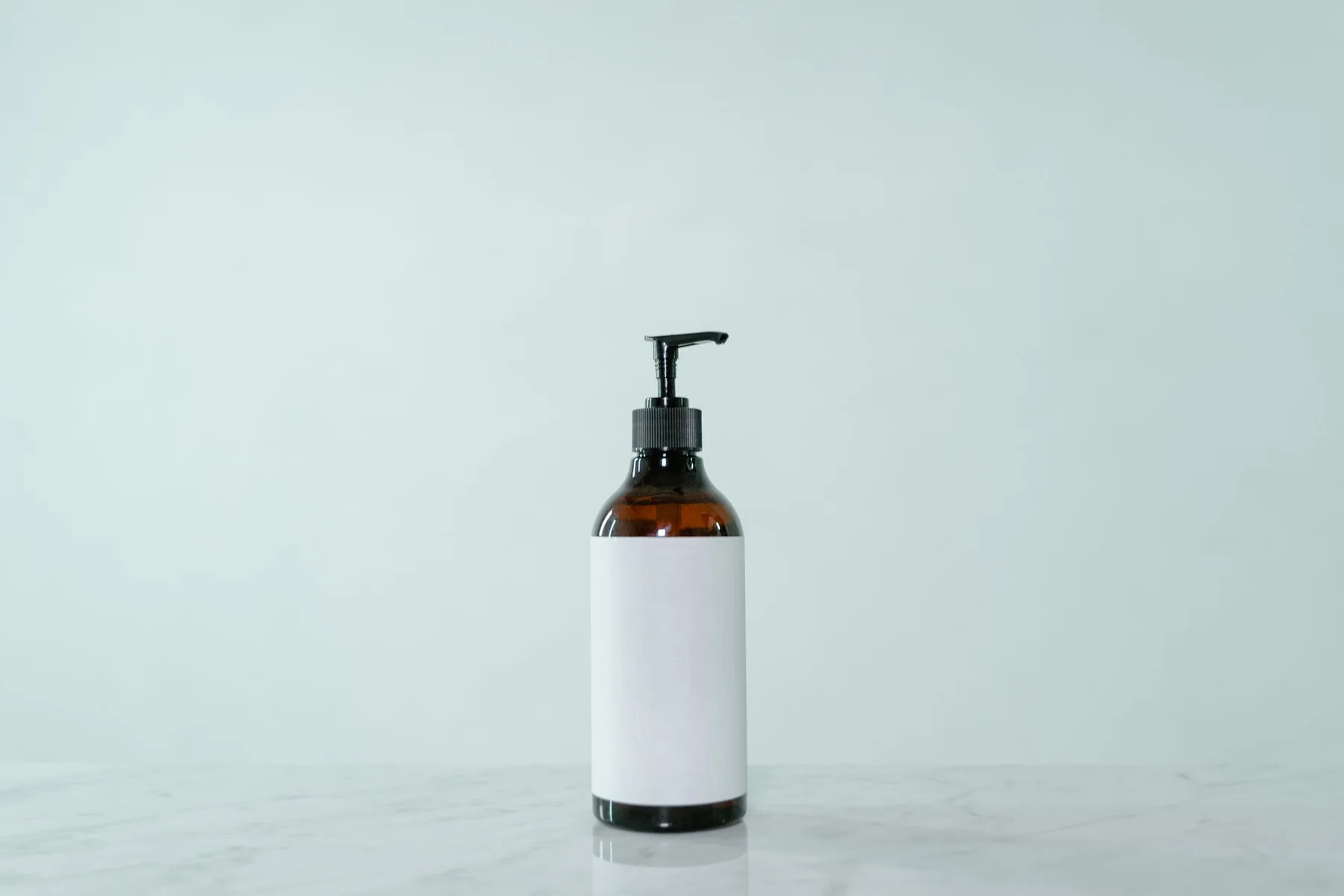 Amber pump bottle with a blank label on a pale studio background